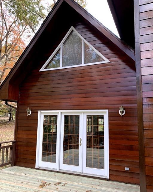 Wooden A-frame cabin exterior with white French doors and triangular windows