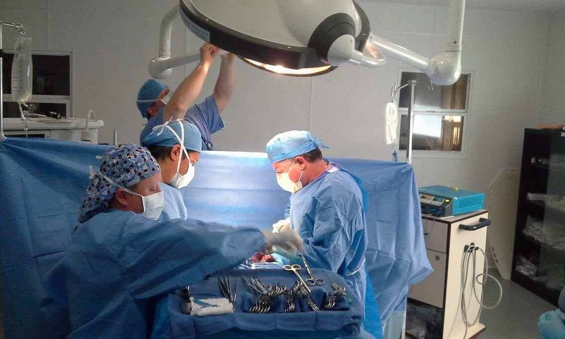 Ein Ärzteteam führt im OP-Saal eine Operation durch, der von OP-Lampen beleuchtet wird.