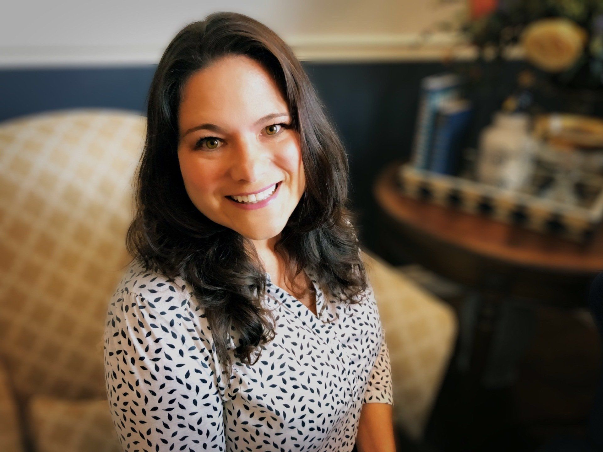 A woman is sitting in a chair and smiling for the camera.