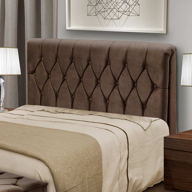 Cabeceira marrom com botões estofados em uma cama com roupa de cama clara.