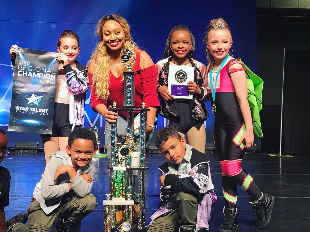 A group of children are posing for a picture with a trophy.