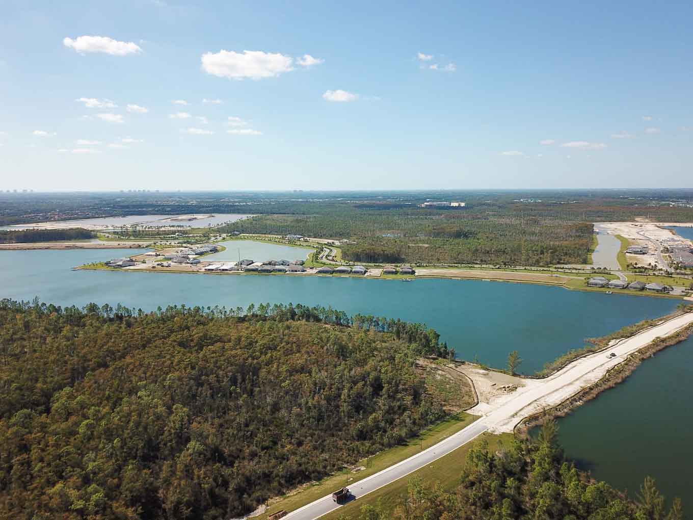 An aerial view of a lake surrounded by trees and a road.