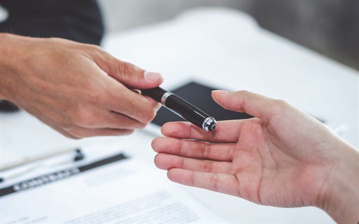A person is handing a pen to another person.