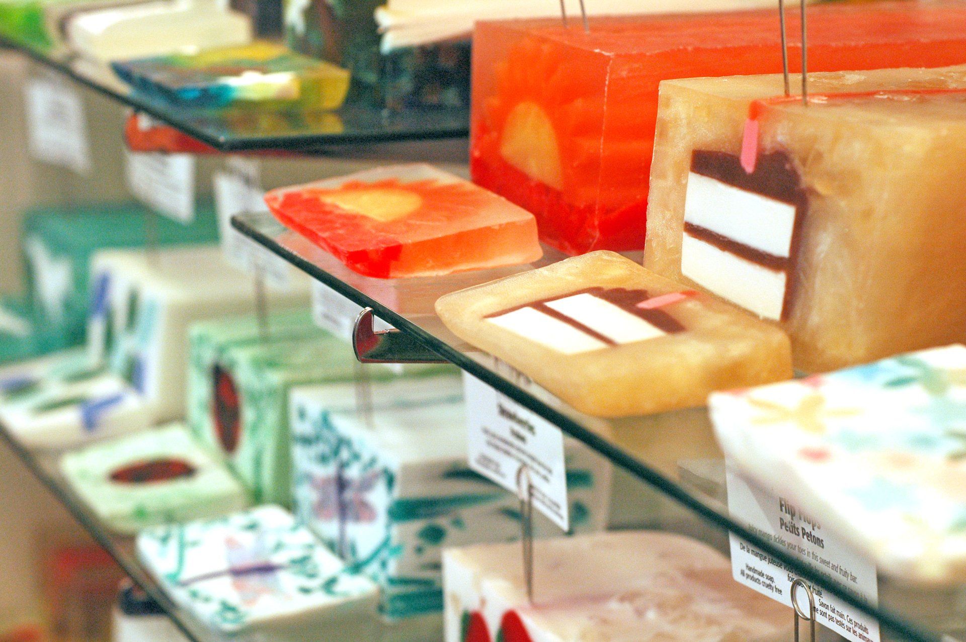 A variety of soaps are displayed on a glass shelf