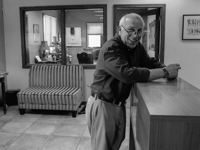 A black and white photo of a man leaning on a counter