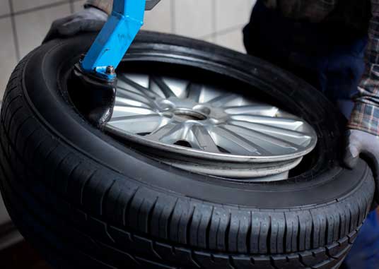 Mechanic removes car tire closeup