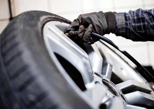 Tire pressure check Closeup of mechanic inflating tyre with alloy wheel