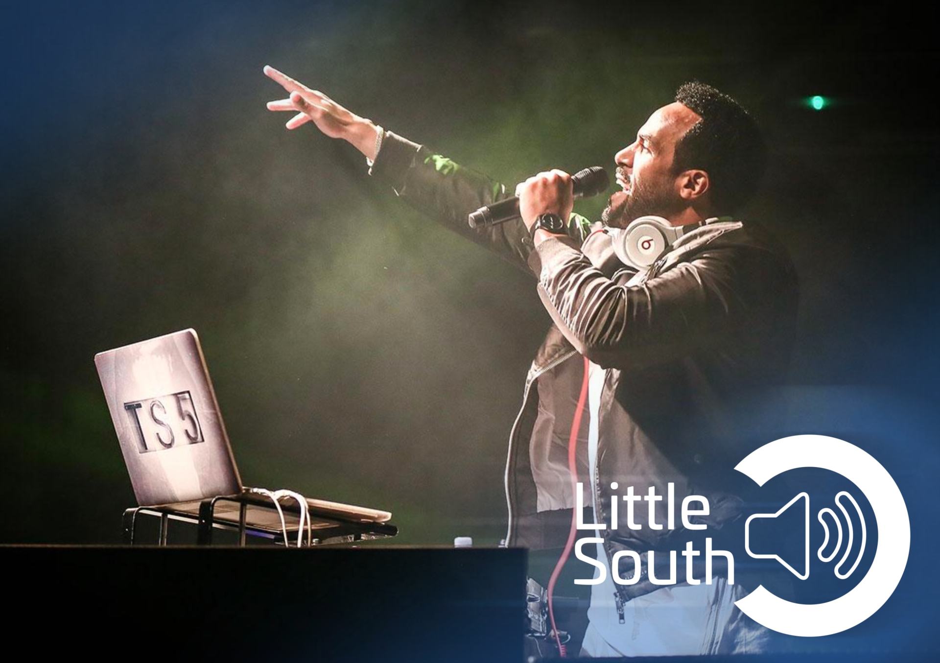A man singing into a microphone in front of a little south logo