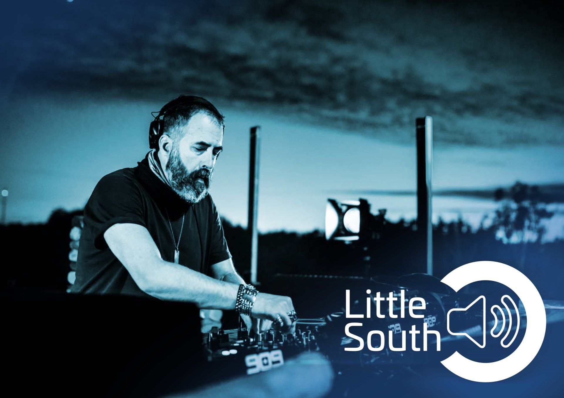 A man with a beard is playing music in front of a sign that says little south