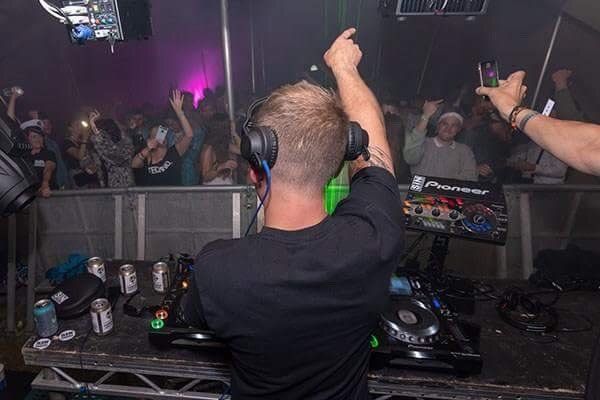A man wearing headphones is playing music at a party.