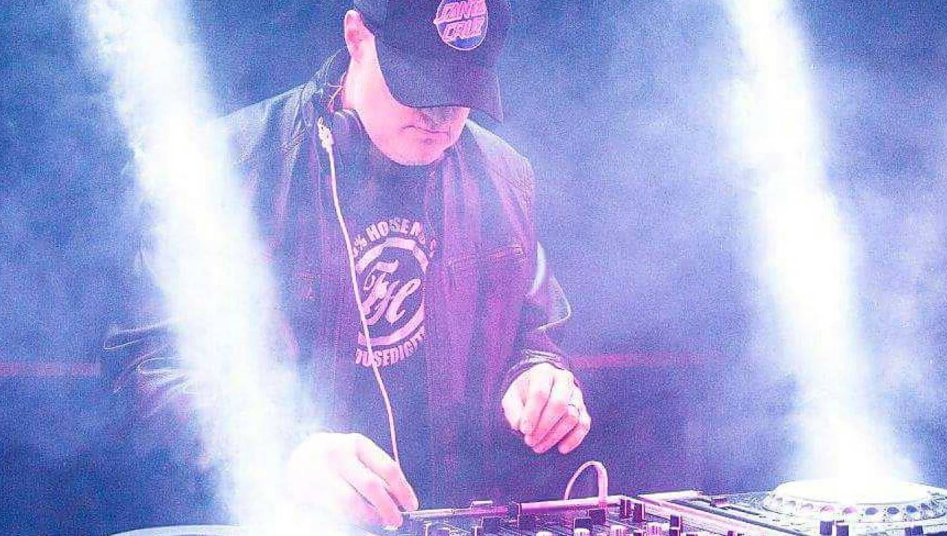A man is playing a dj set in a dark room.