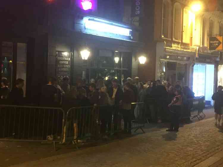A large group of people are standing outside of a building at night.