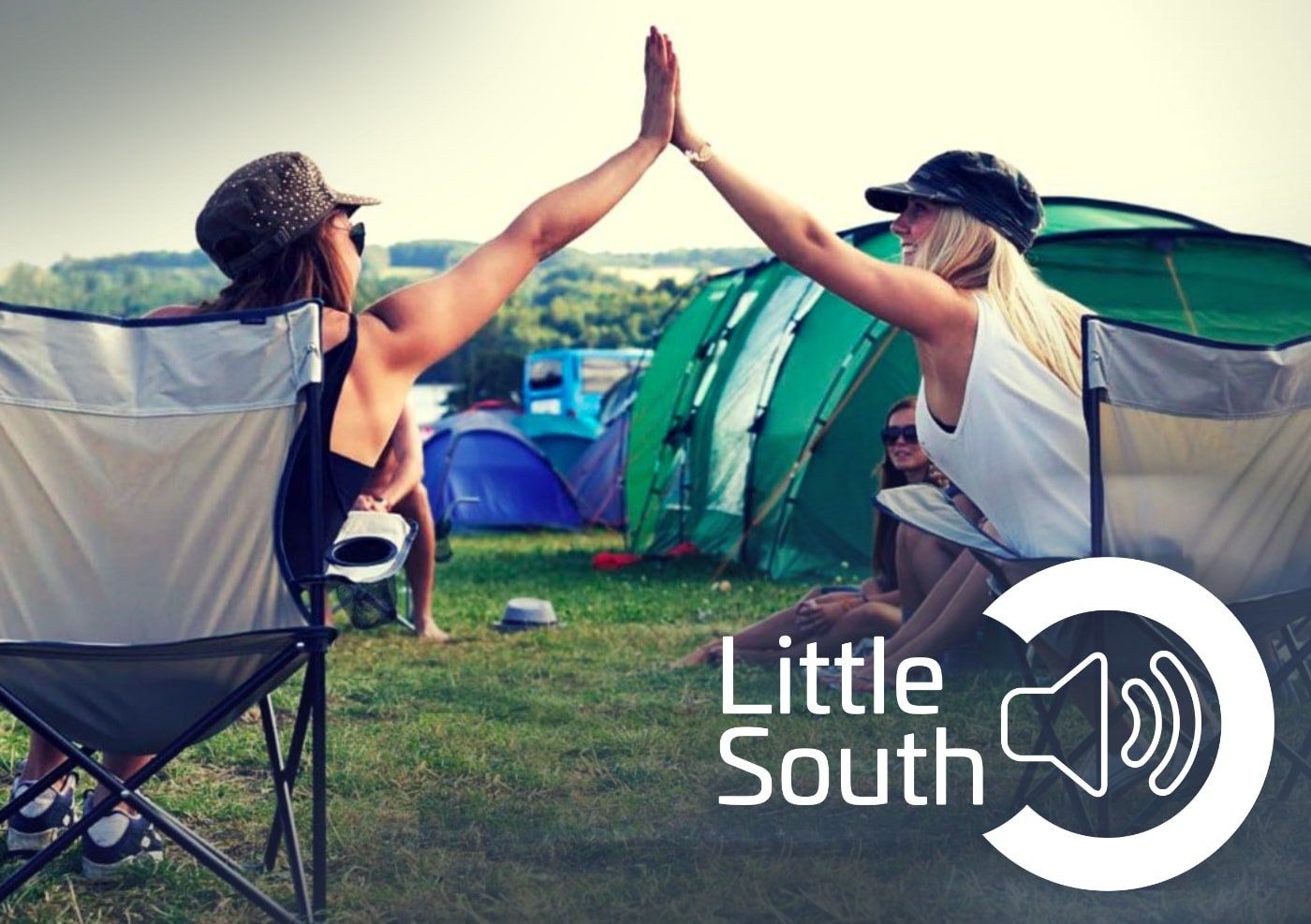 Two women give each other a high five in front of tents
