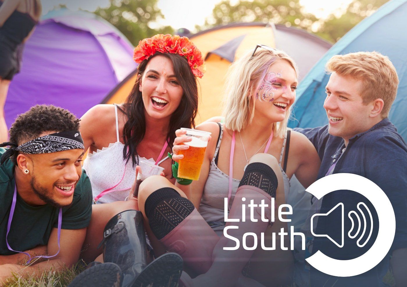A group of people are sitting in front of tents at a festival.