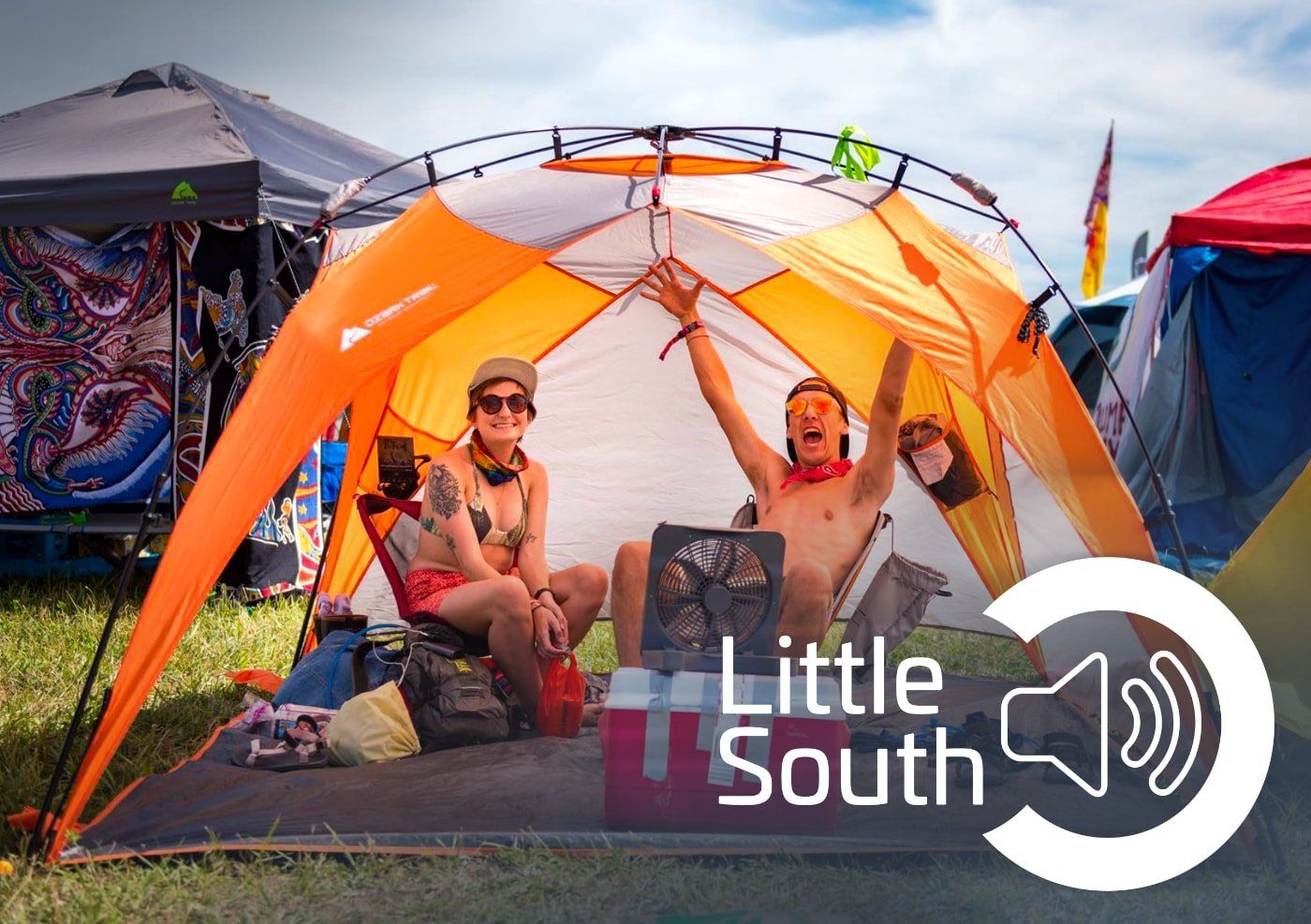 A man and a woman are sitting inside of an orange tent.