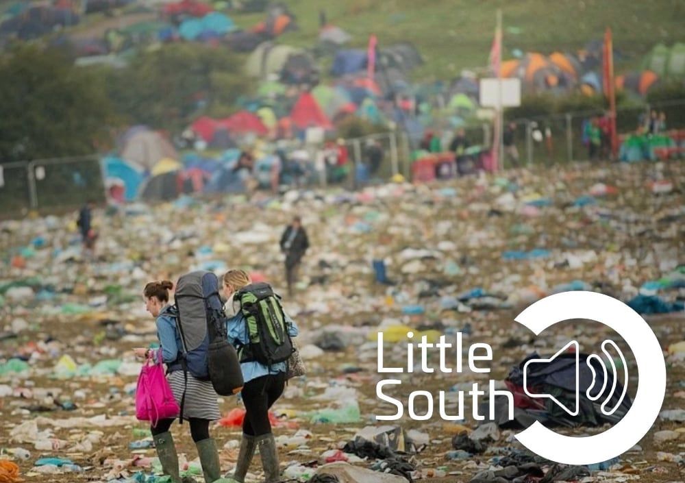 Two people are standing in a pile of trash at a festival.
