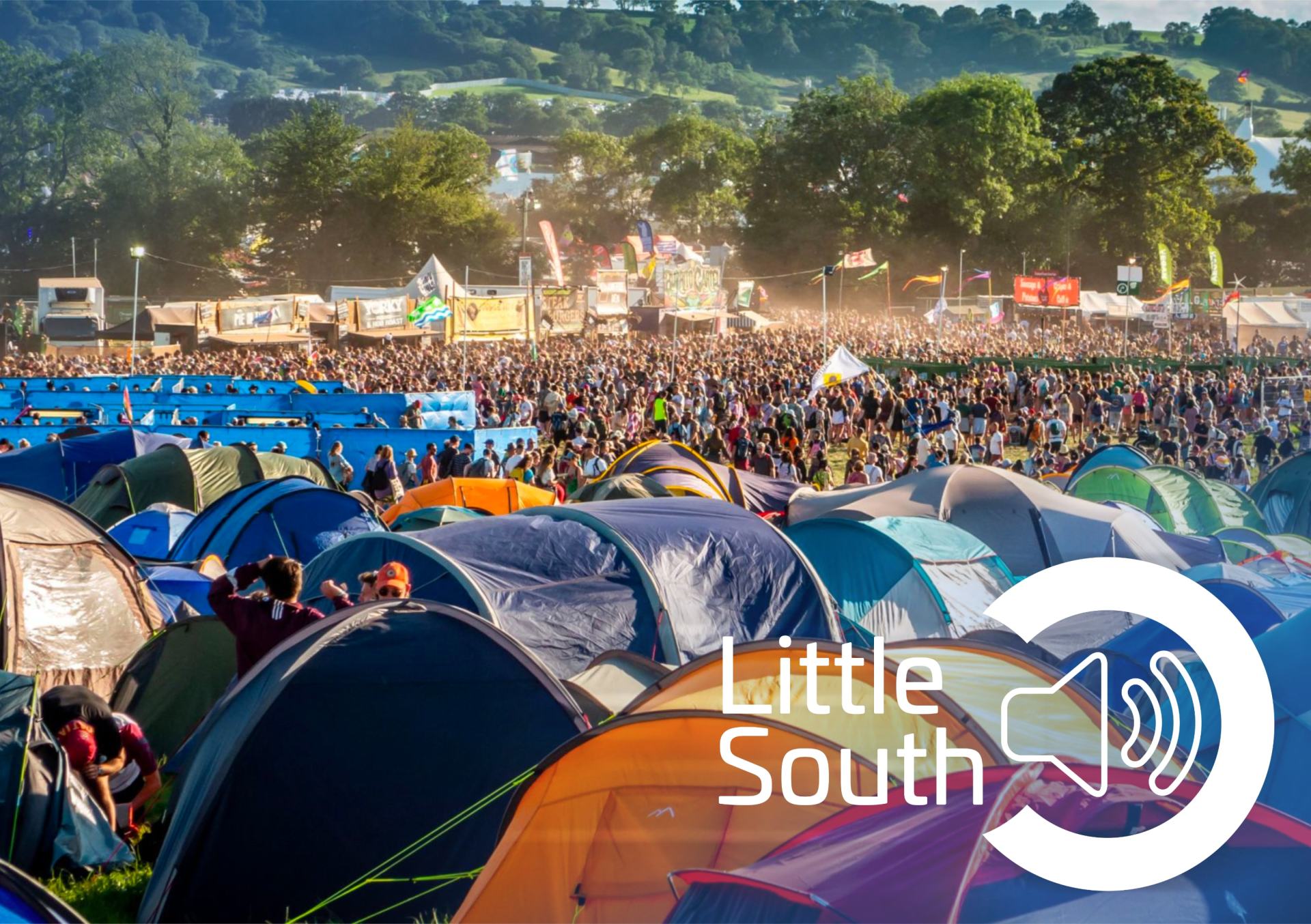 A large crowd of people are gathered in a field of tents at a little south festival.