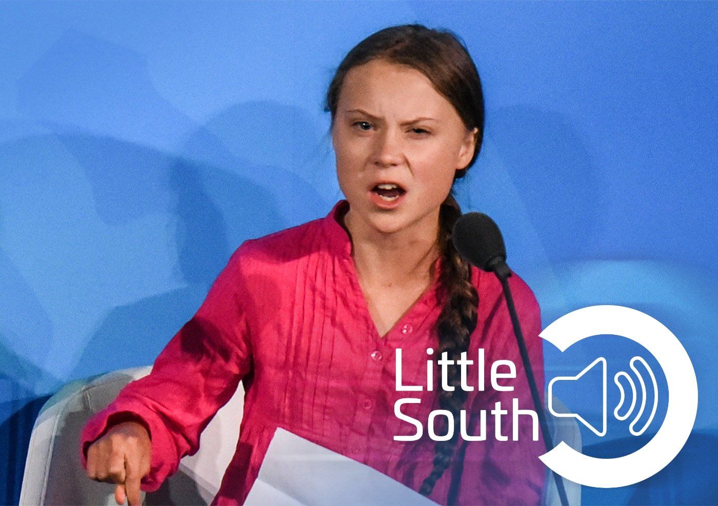 A woman in a pink shirt is speaking into a microphone.