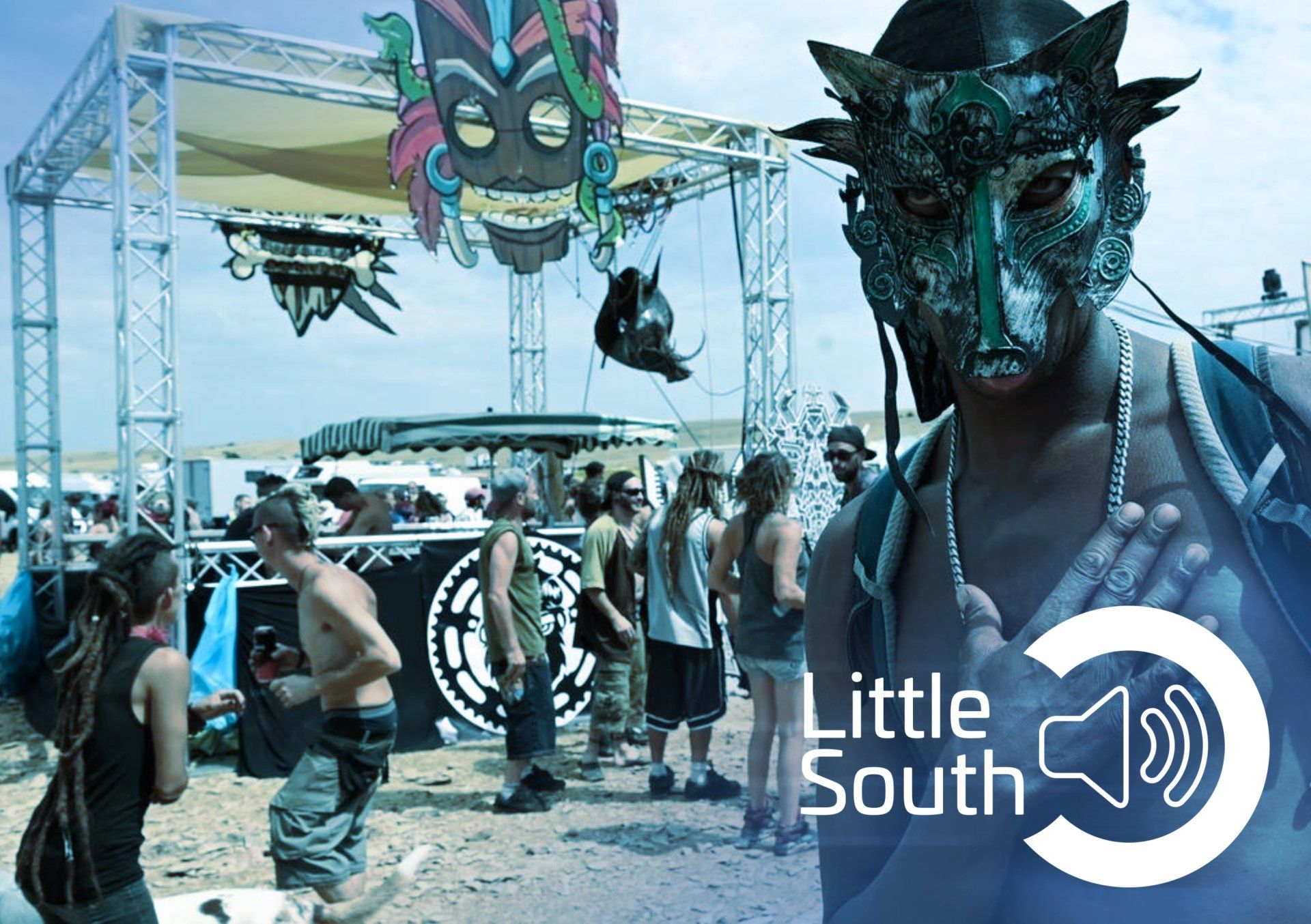A man wearing a mask stands in front of a sign that says little south