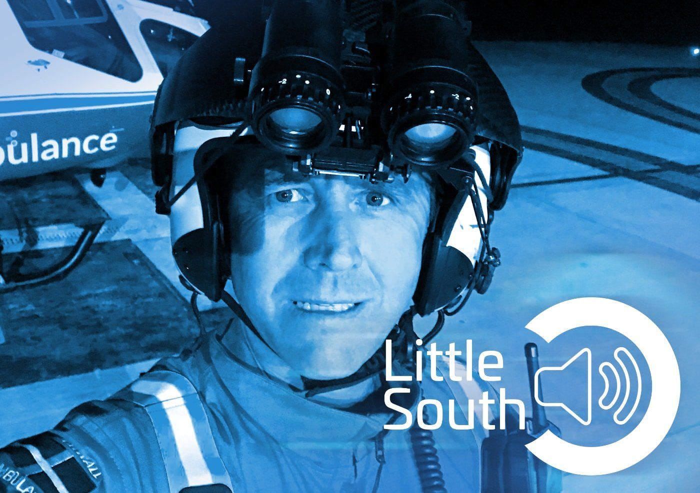A man wearing a helmet and goggles is standing in front of an ambulance that says little south