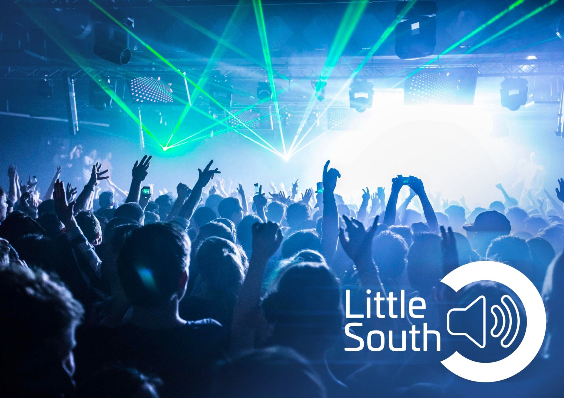 A crowd of people are standing in front of a stage at a concert.
