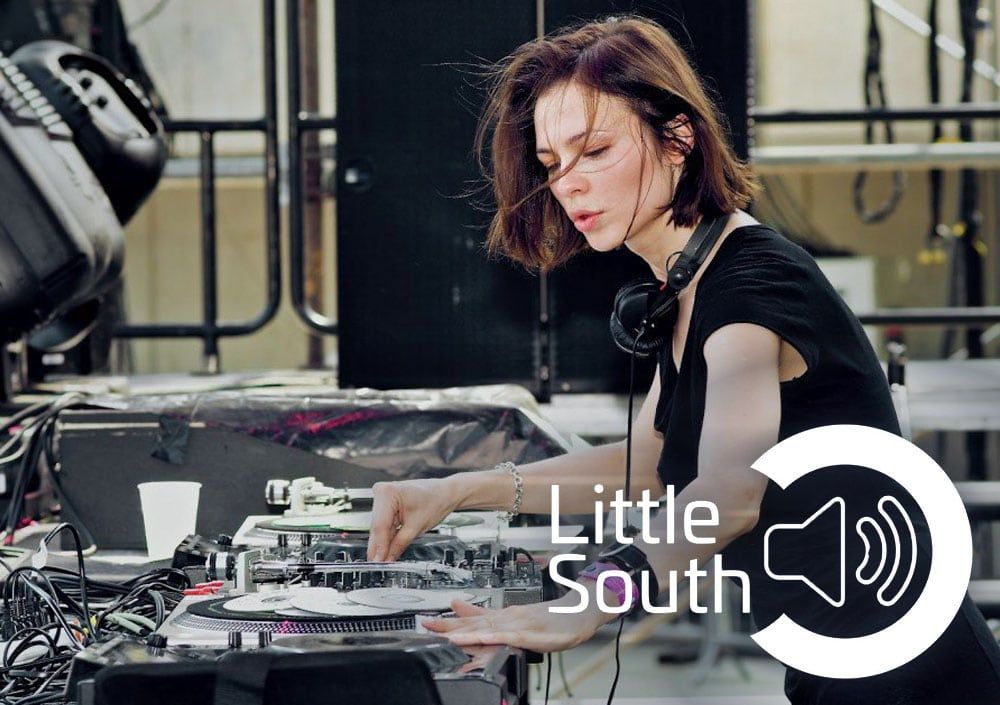 A woman wearing headphones is playing music at a little south event