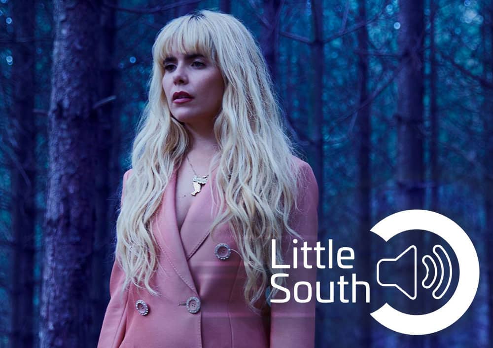 A woman in a pink suit is standing in the middle of a forest.