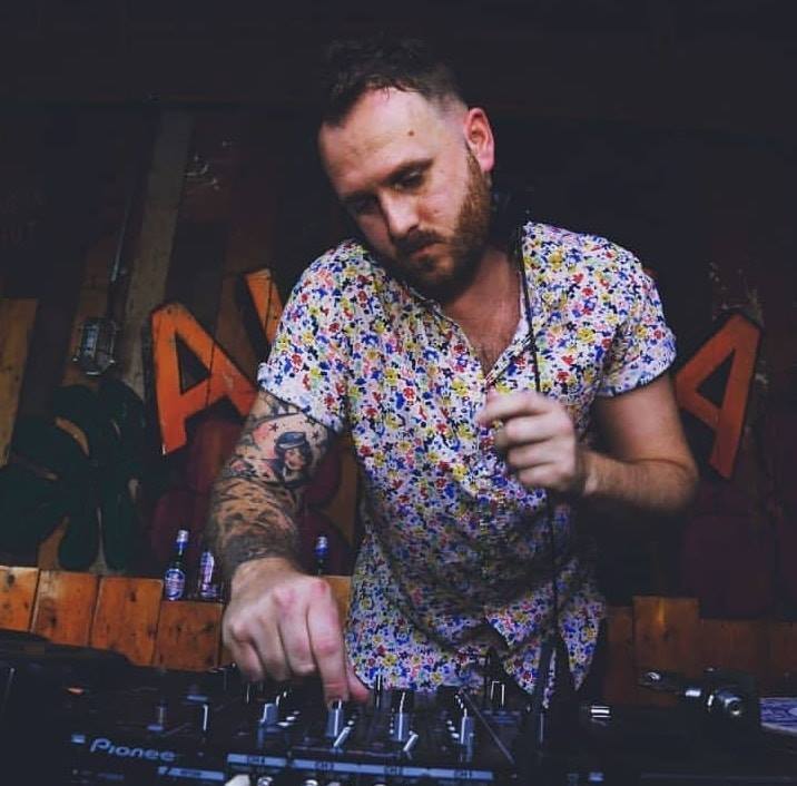 A man in a floral shirt is playing music on a pioneer dj controller.