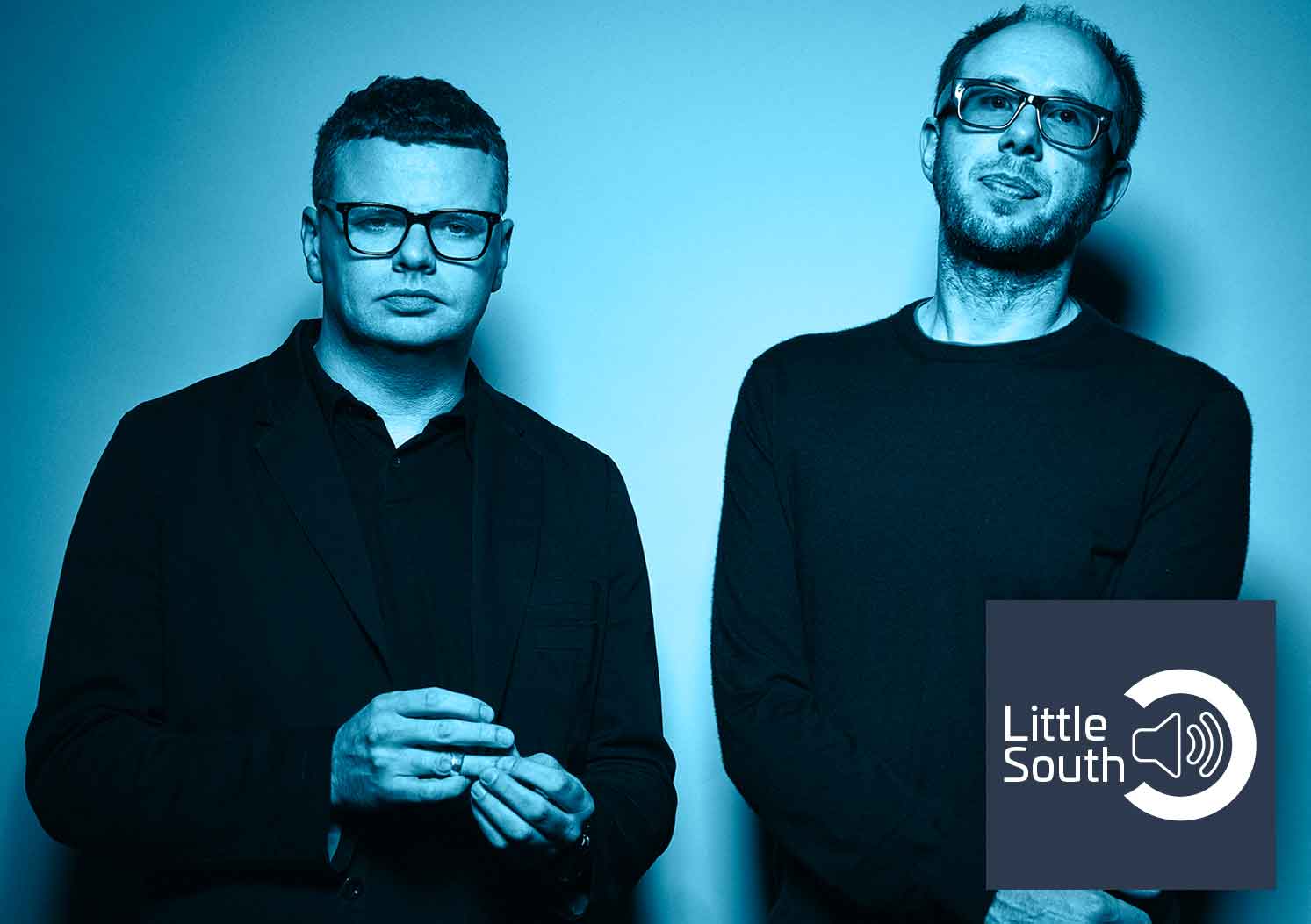 Two men standing next to each other with a little south logo in the background