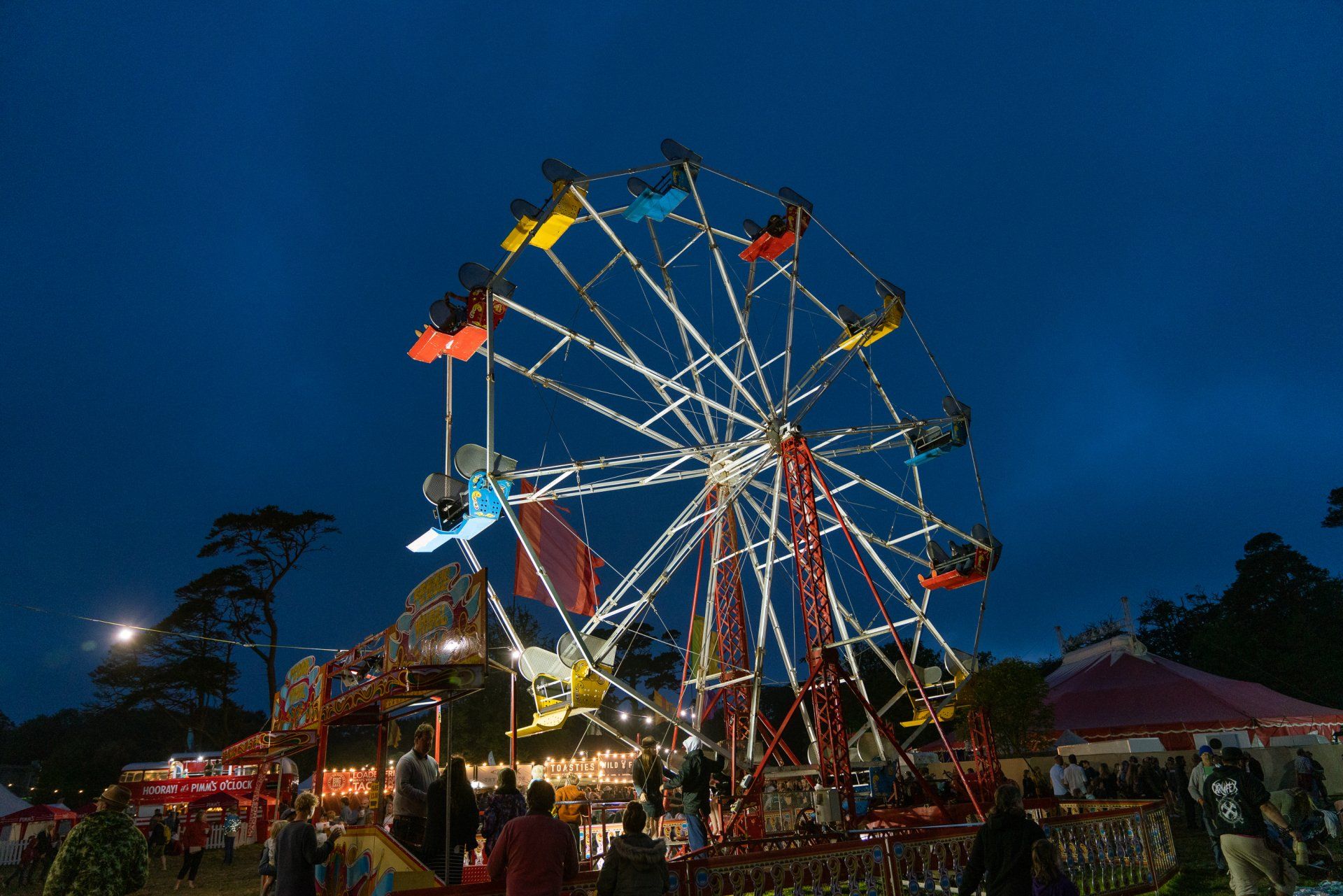 A ferris wheel is lit up at night at a carnival