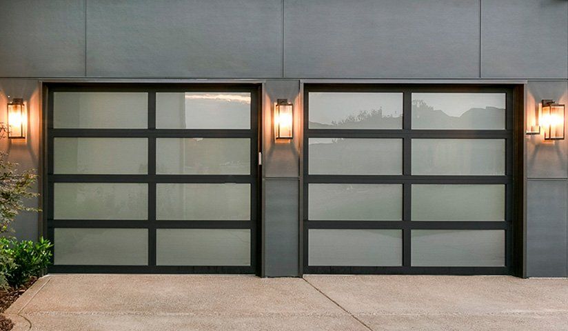 Two modern garage doors with frosted glass panels and black frames, flanked by wall sconces.