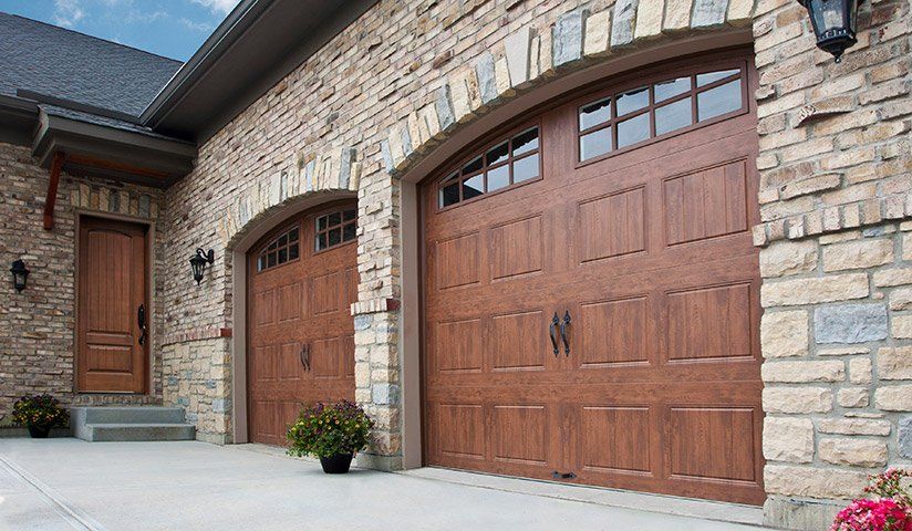 Brown garage doors with arched tops and stone exterior.
