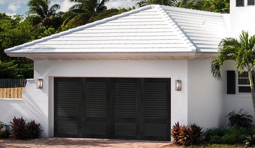 White house with black garage door, white roof.