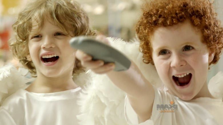 Dois meninos vestidos de anjos seguram um controle remoto.