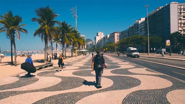 Um homem está andando por uma calçada perto de uma praia.