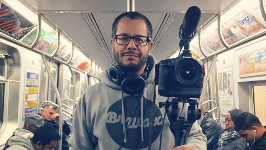 Um homem está segurando uma câmera em um tripé em um vagão do metrô.