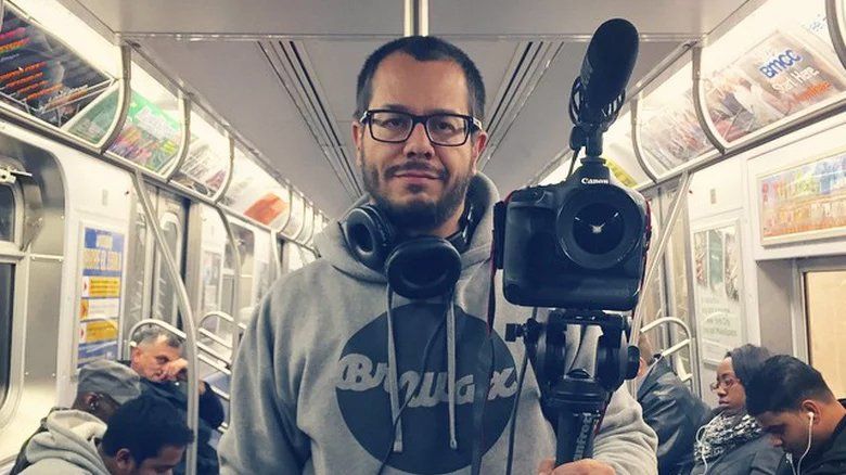 Um homem está segurando uma câmera em um vagão do metrô.