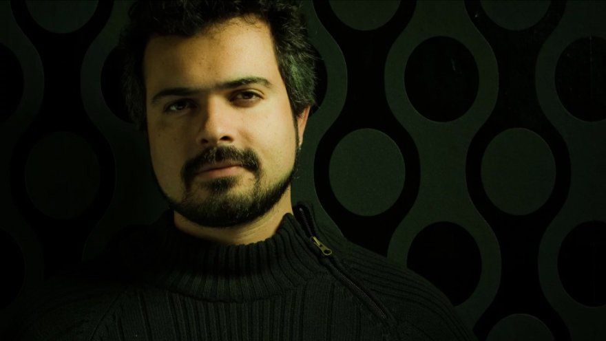 Um homem com barba está vestindo um suéter preto.