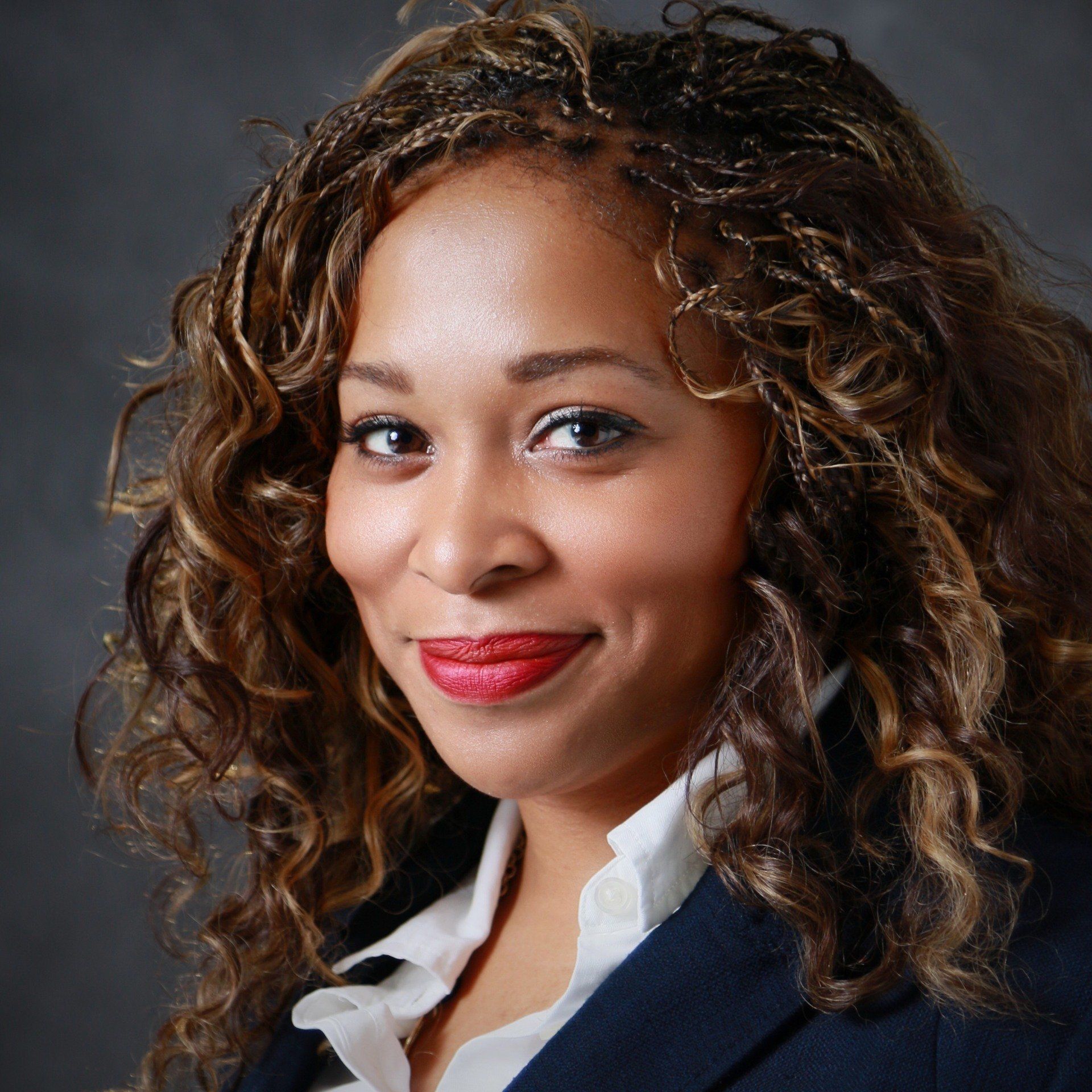 A woman with curly hair is wearing a blue jacket and white shirt