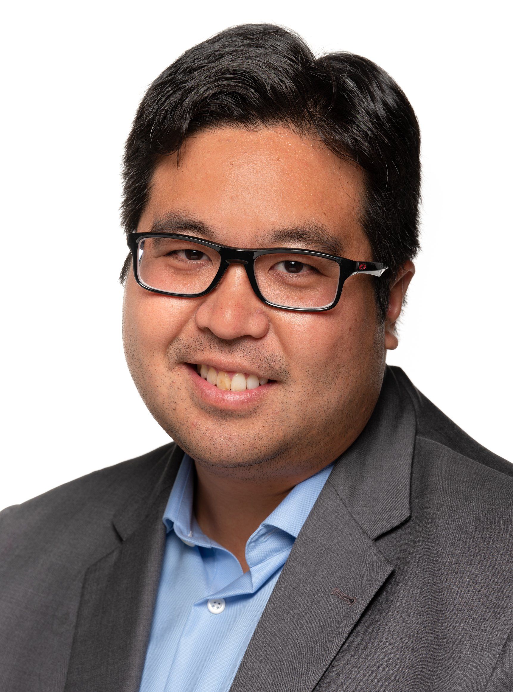 A man wearing glasses and a suit is smiling for the camera