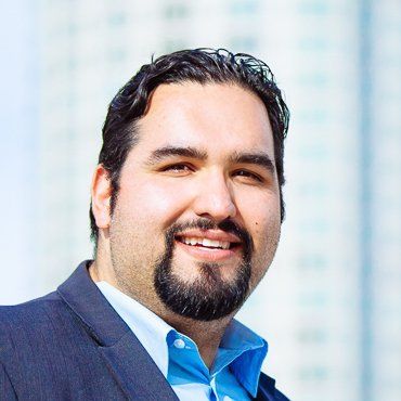 A man with a beard is wearing a suit and smiling.