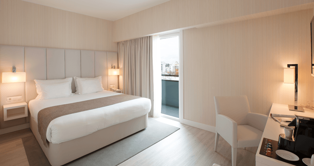 Um quarto de hotel com uma cama king size, escrivaninha e cadeira.