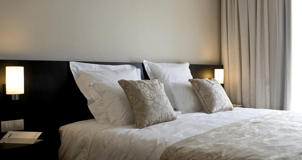 Uma cama com lençóis e travesseiros brancos em um quarto de hotel