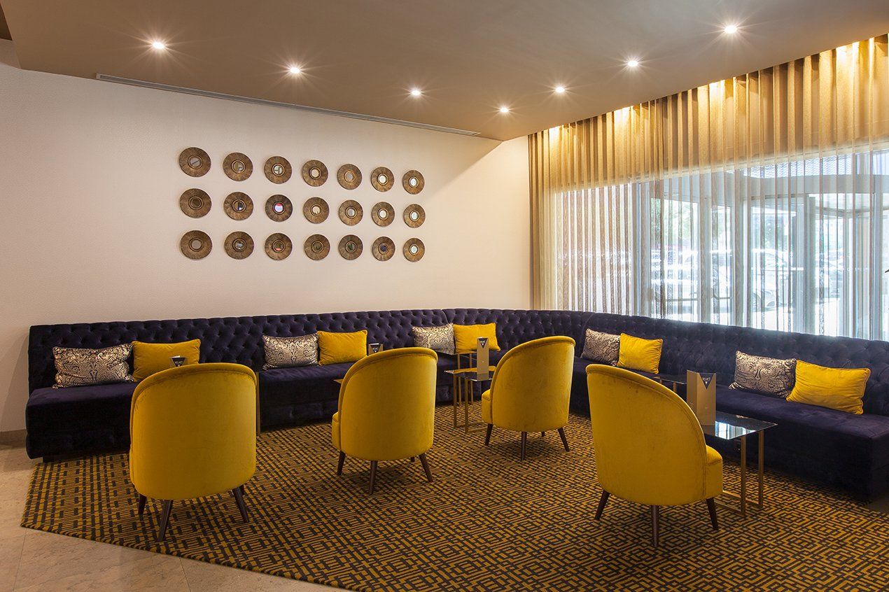 Uma sala de estar com cadeiras amarelas e sofás azuis.