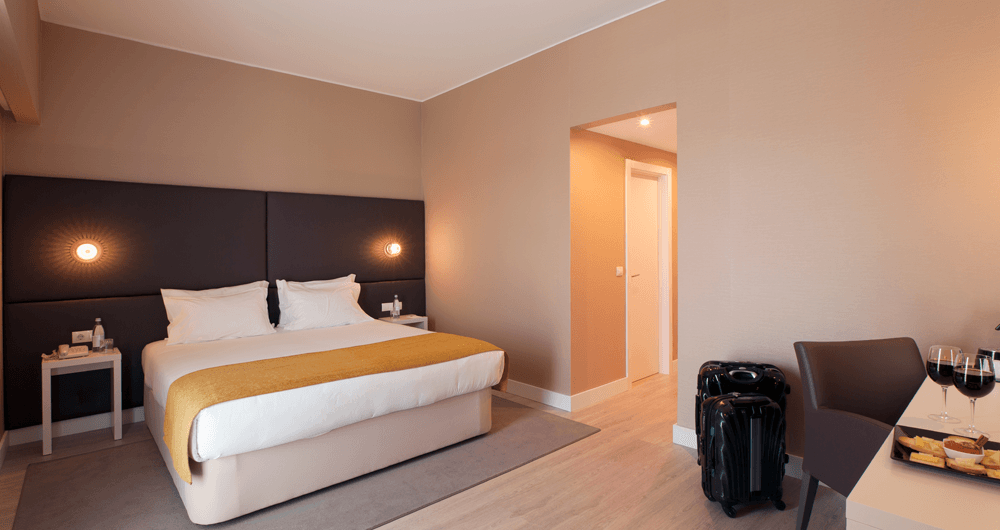 Um quarto de hotel com uma cama king size e uma mala no chão.