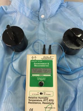A device is sitting on top of a blue striped shirt.