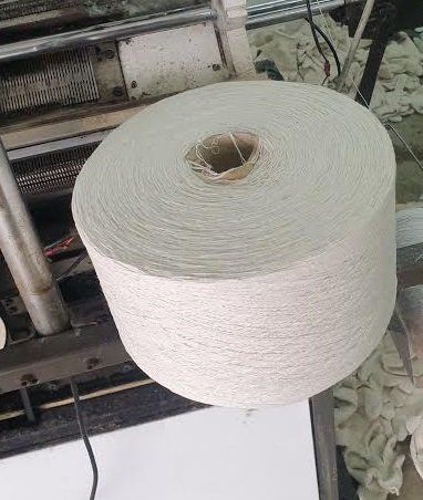 A roll of white yarn is sitting on top of a table.