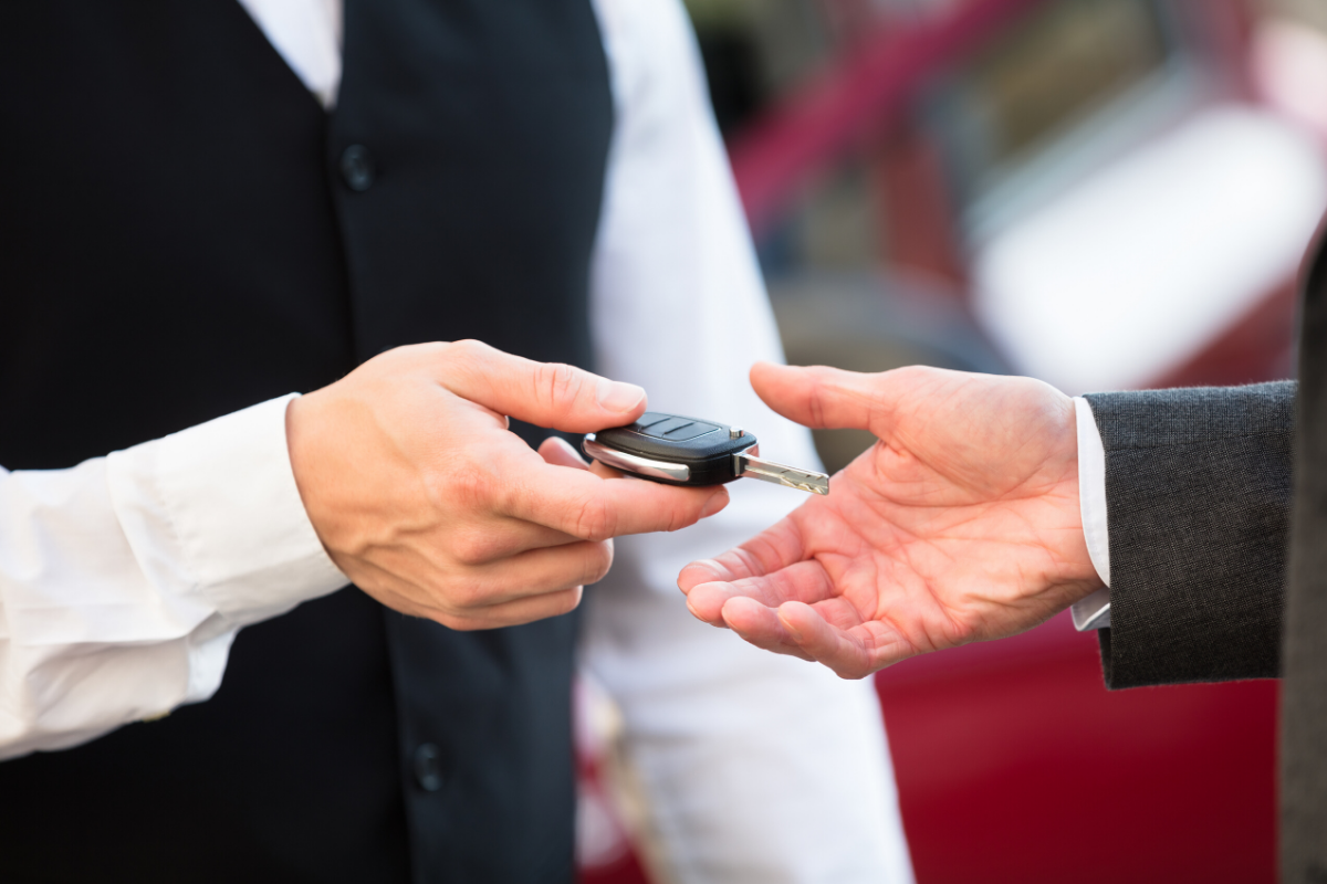 A man is handing a car key to another man.