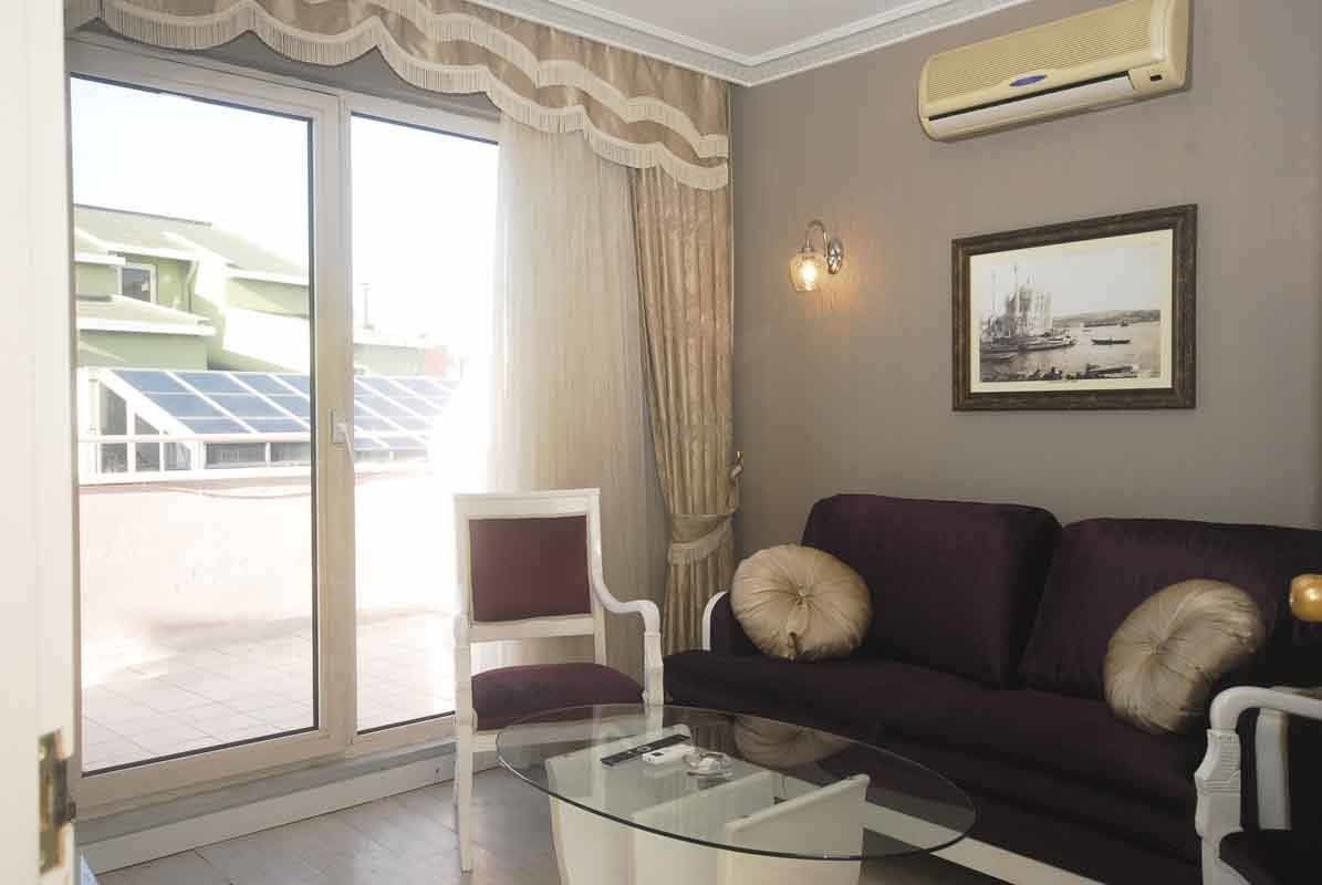 A living room with a purple couch , chairs , and a glass coffee table.