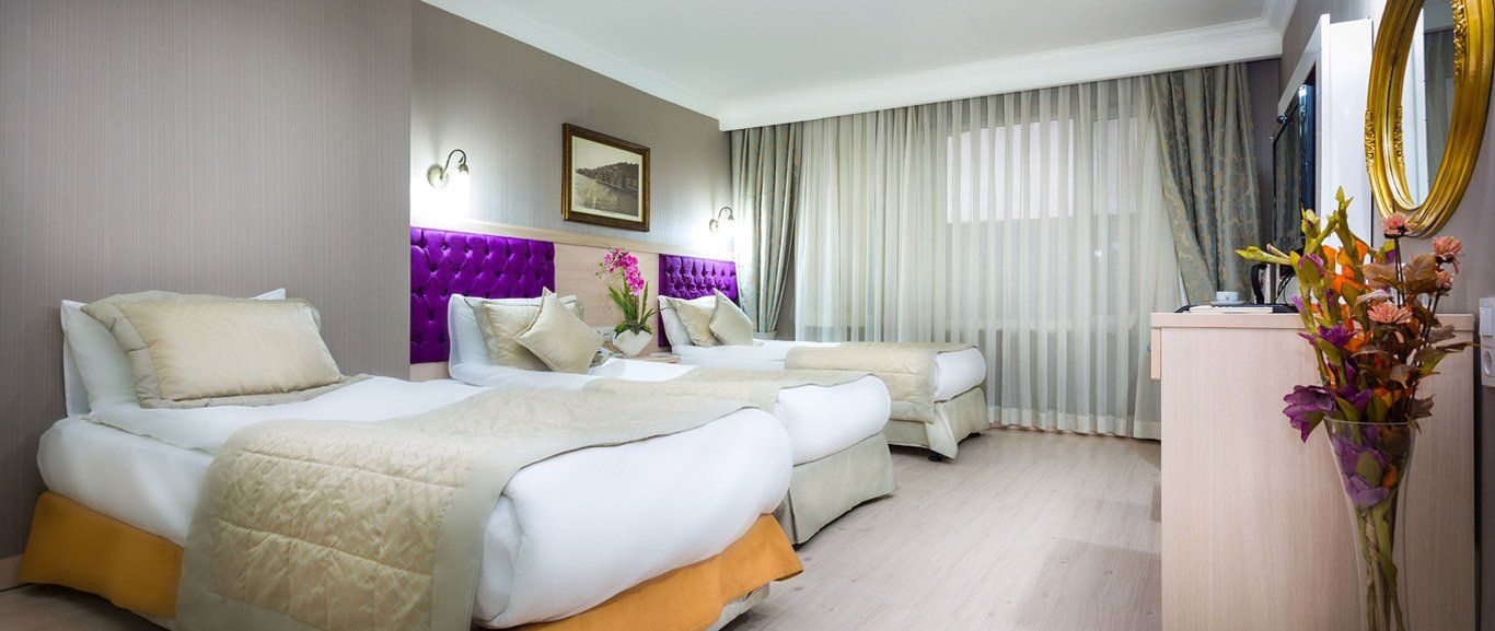 A hotel room with three beds and a television.